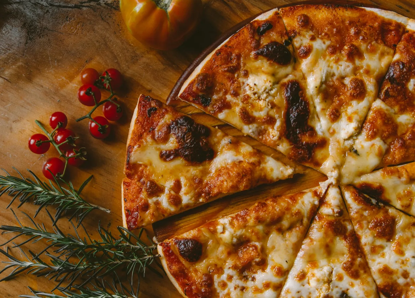 Pizza au fromage découpée, vue du dessus, romarin et tomates cerises